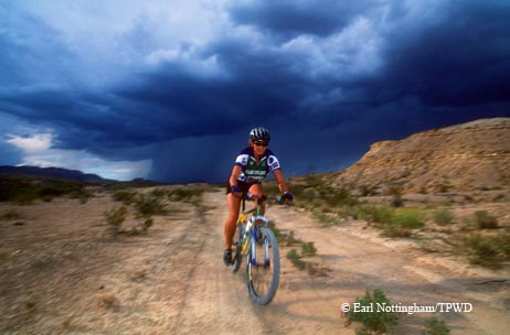 A mountain biker works to outrun a sudden desert downpour near Lajitas.