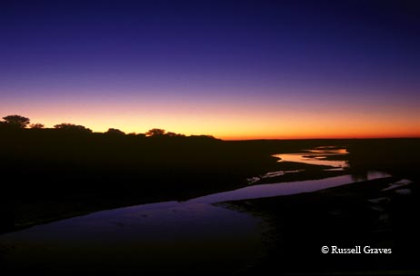 The colors of the sunrise paint the sky, reflected in the Pease River near Paducah.