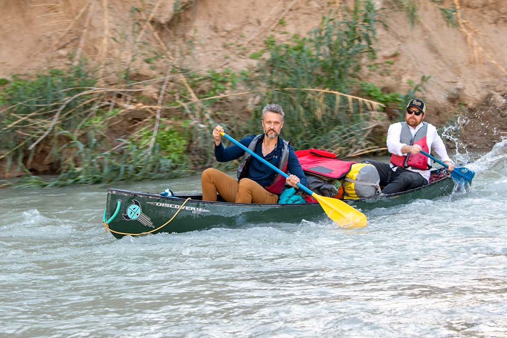 two paddlers in loaded canoe taking on rapids