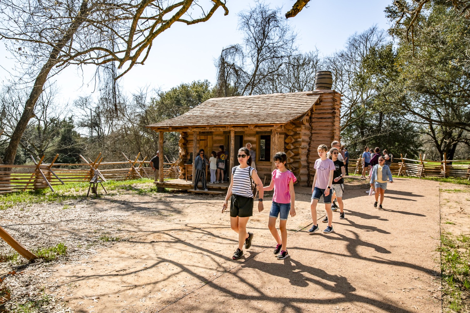a tour group walks in front of a log  cabin