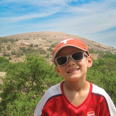Photo of a little boy in an orange hat in front of a boulder