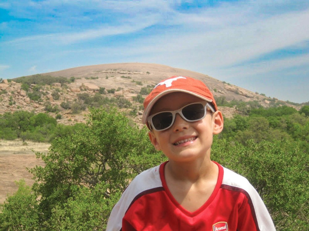Photo of a little boy in an orange hat in front of a boulder