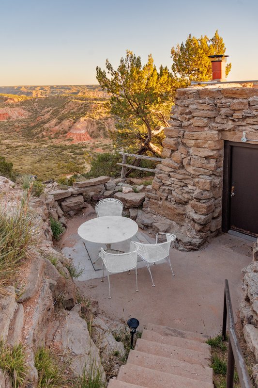 White bistro table on a deck outside a cabin overlooking a canyon