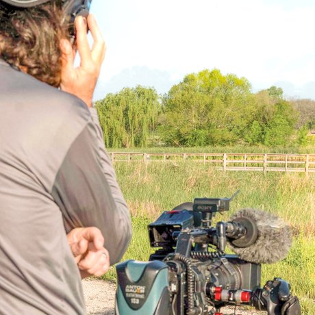 Abe Moore stands behind his camera conducting an interview for the TPWD PBS Tv Show