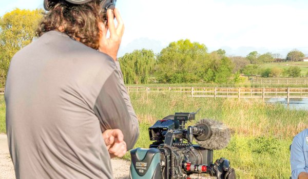 Abe Moore stands behind his camera conducting an interview for the TPWD PBS Tv Show