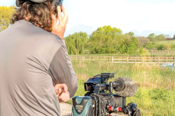 Abe Moore stands behind his camera conducting an interview for the TPWD PBS Tv Show