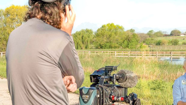 Abe Moore stands behind his camera conducting an interview for the TPWD PBS Tv Show