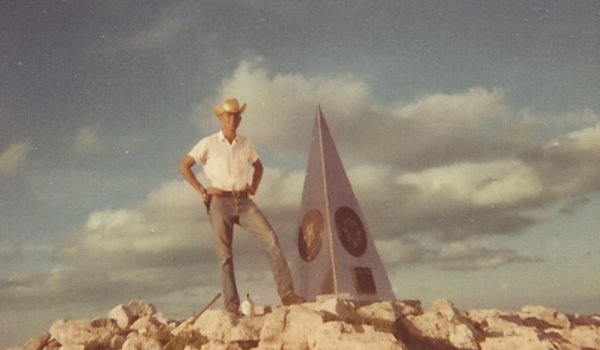 Raymond Urban next to a monument on Guadalupe Peak.
