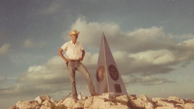 Raymond Urban next to a monument on Guadalupe Peak.