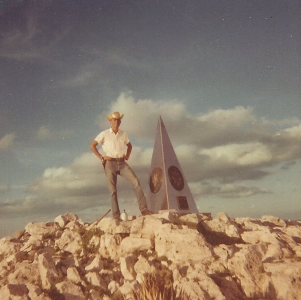 Raymond Urban next to a monument on Guadalupe Peak.