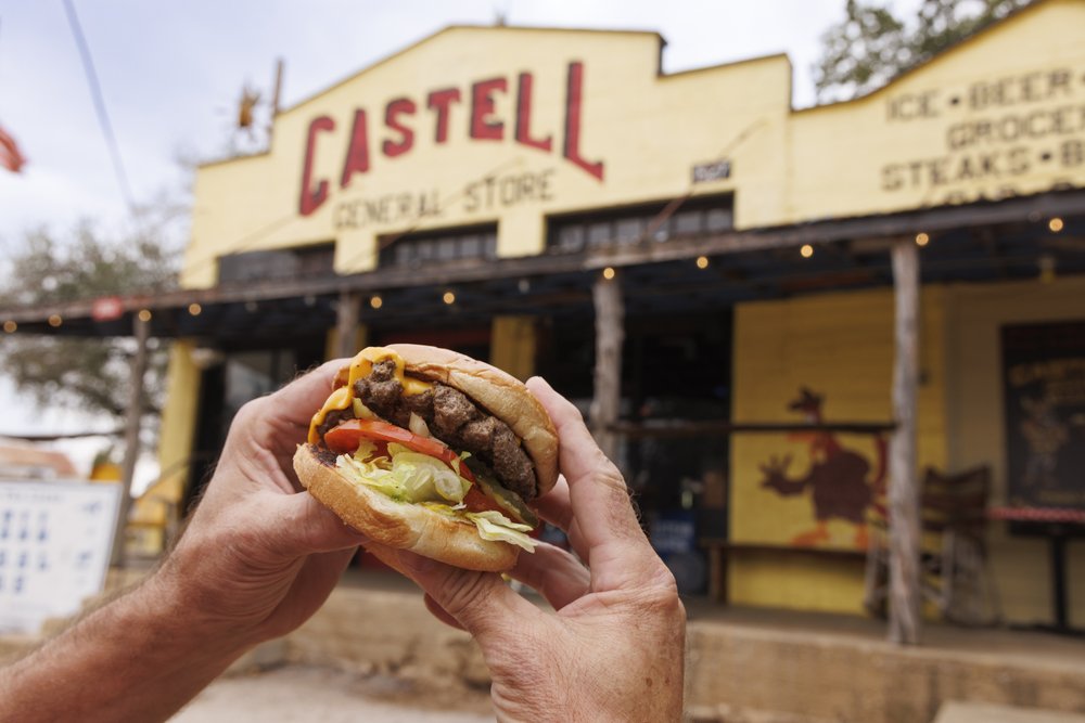 Hands holding a cheeseburger outside the Castell General Store.