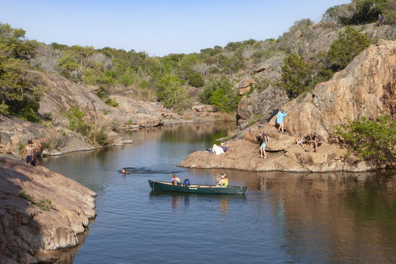 People boating, swimming and climbing at the Devil's Waterhole.