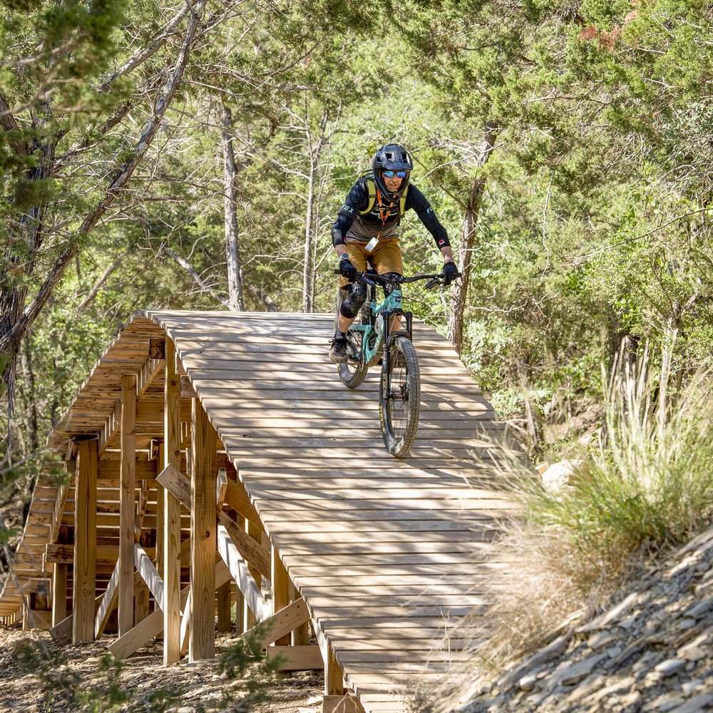 Mountain biker riding on a bridge through the Spider Mountain Trail.