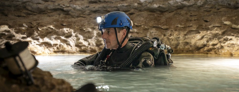 Person preparing to scuba dive into an underwater cave.