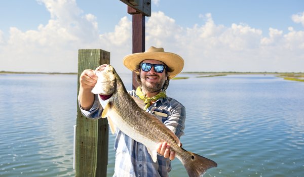 Person in a hat showing off a large fish.