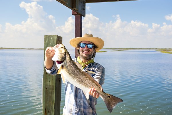 Person in a hat showing off a large fish.