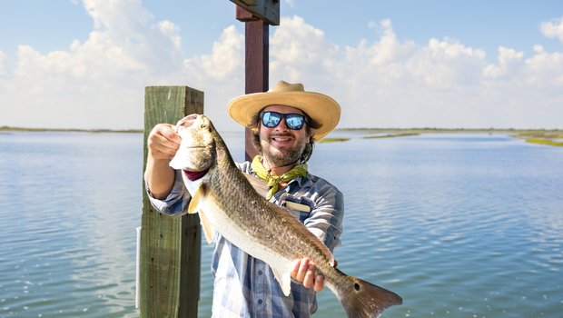 Person in a hat showing off a large fish.