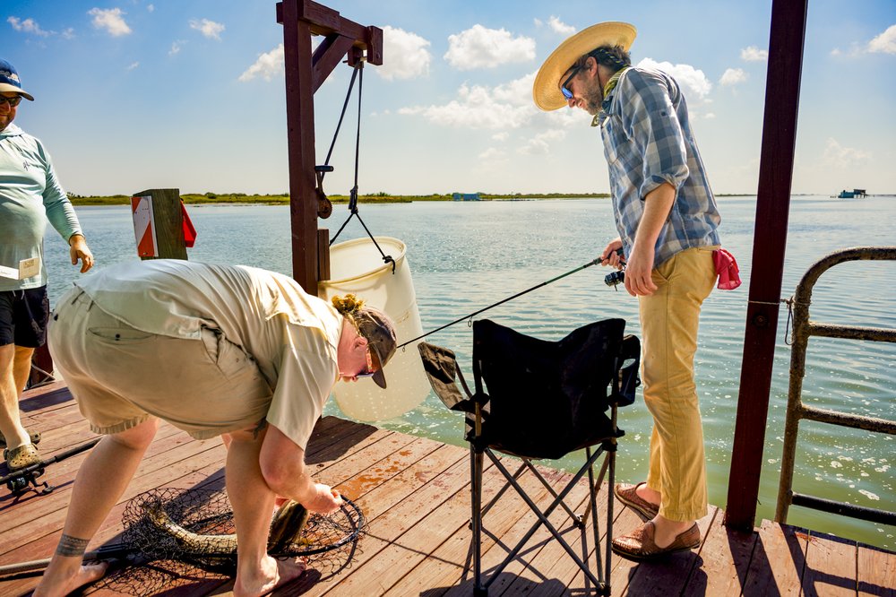 People removing a fish from a hook and net.
