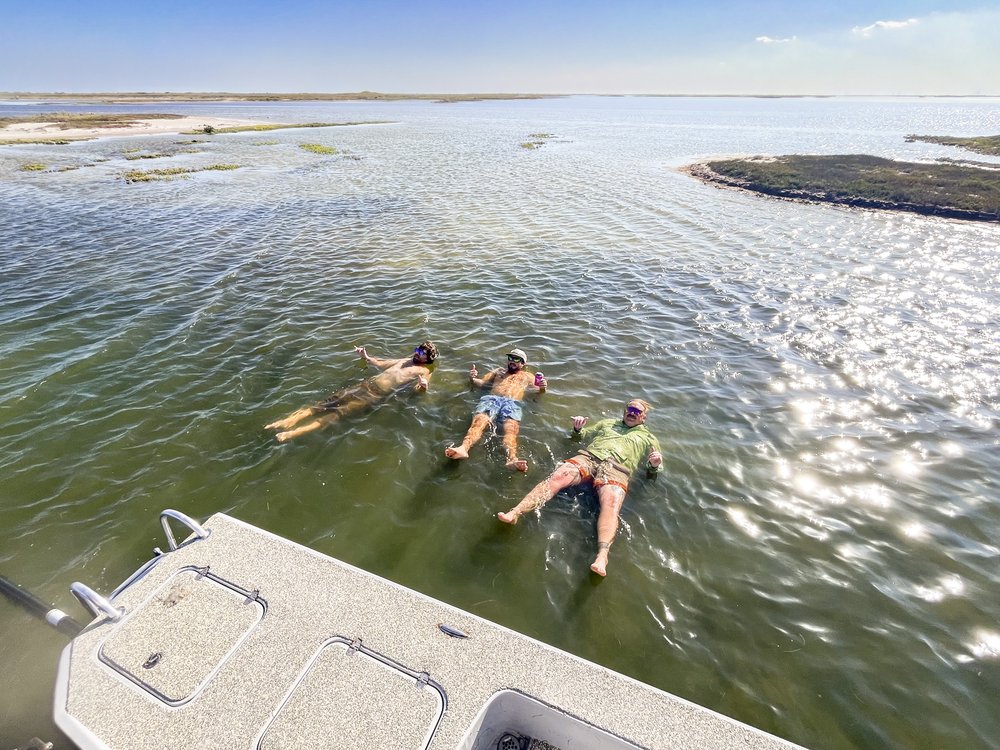 People floating in the water beside a boat.