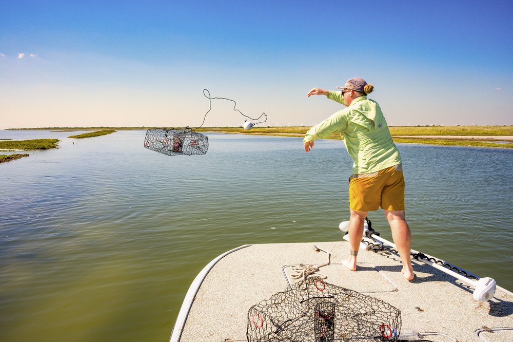A person throwing a crab trap off of a deck.