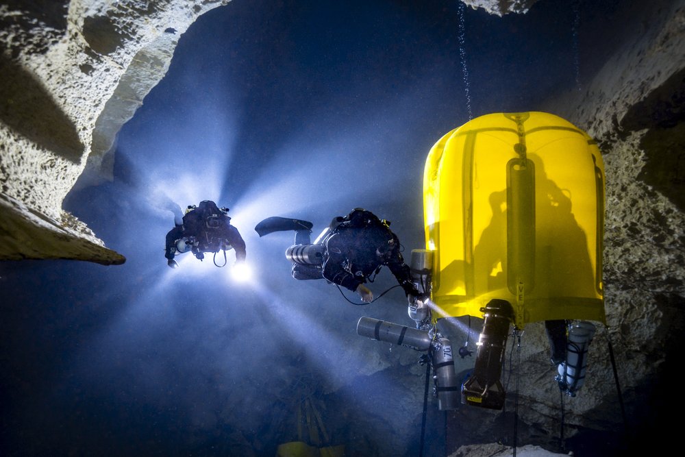 Two scuba divers swimming up to a decompression chamber.