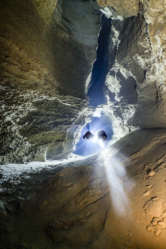 Scuba divers pulling on a nylon cord in an underwater cave.