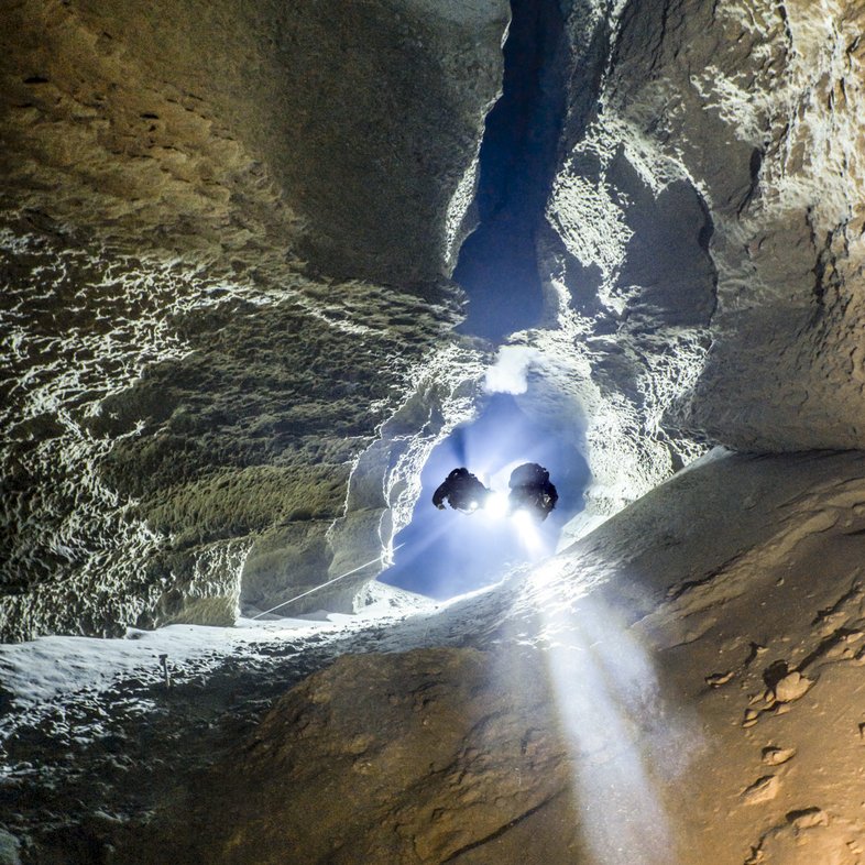 Scuba divers pulling on a nylon cord in an underwater cave.