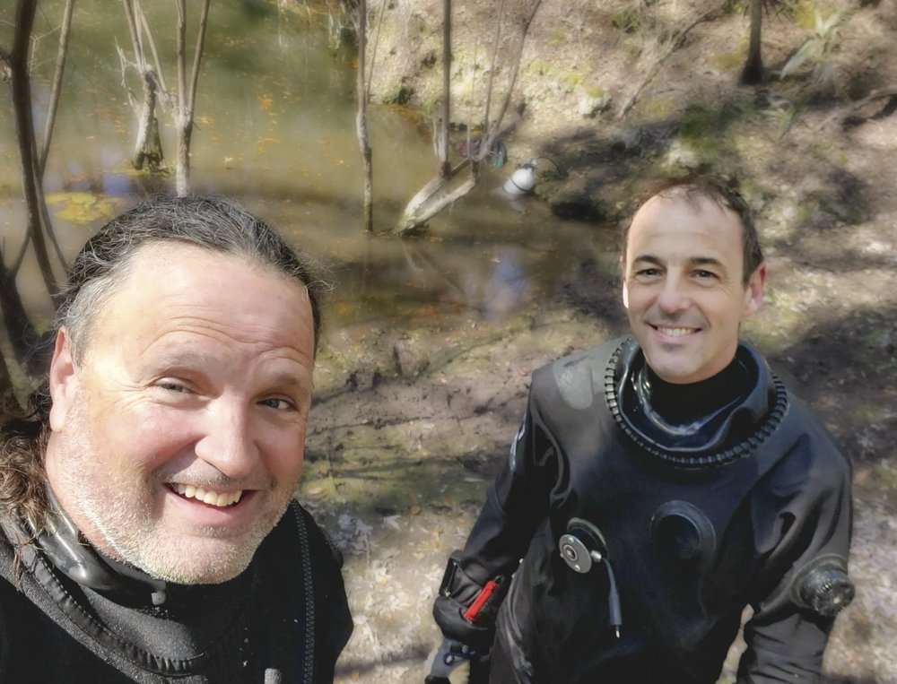 A selfie of two men in scuba gear smiling