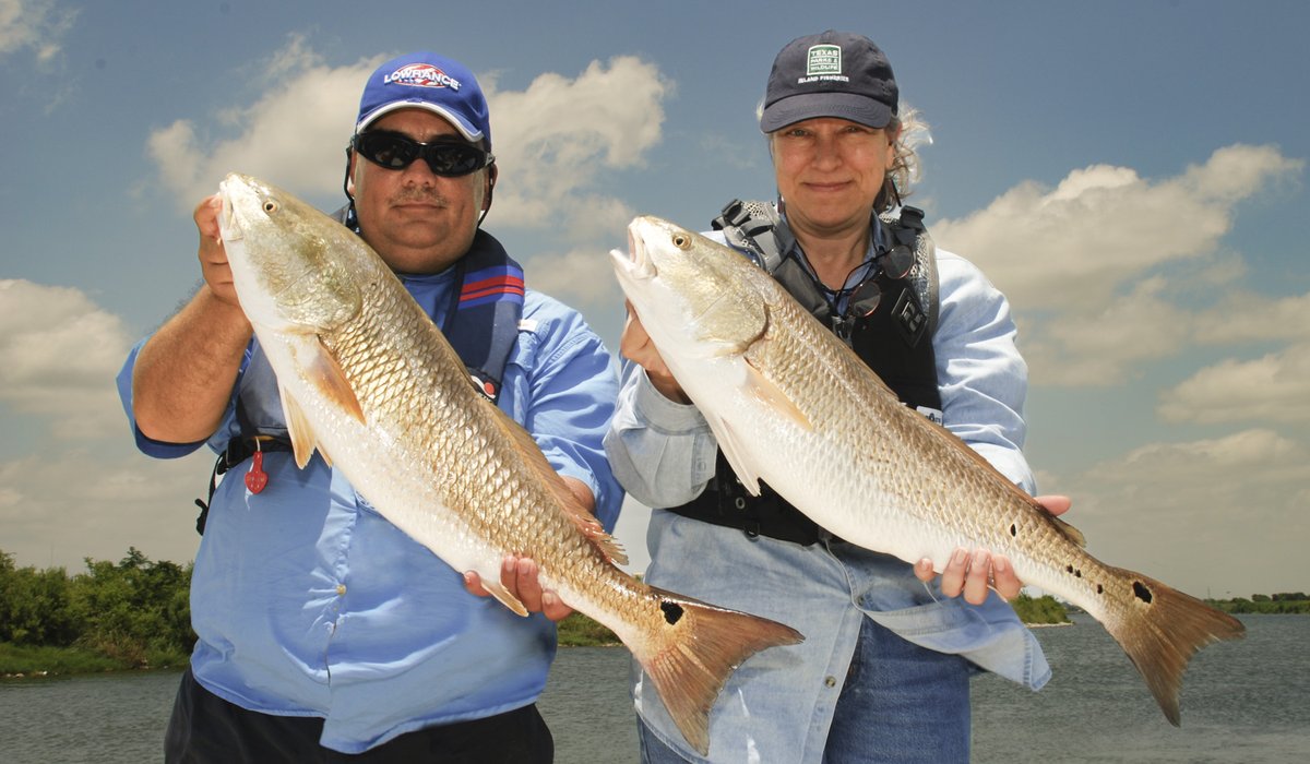 Two people holding up large fish that they caught.