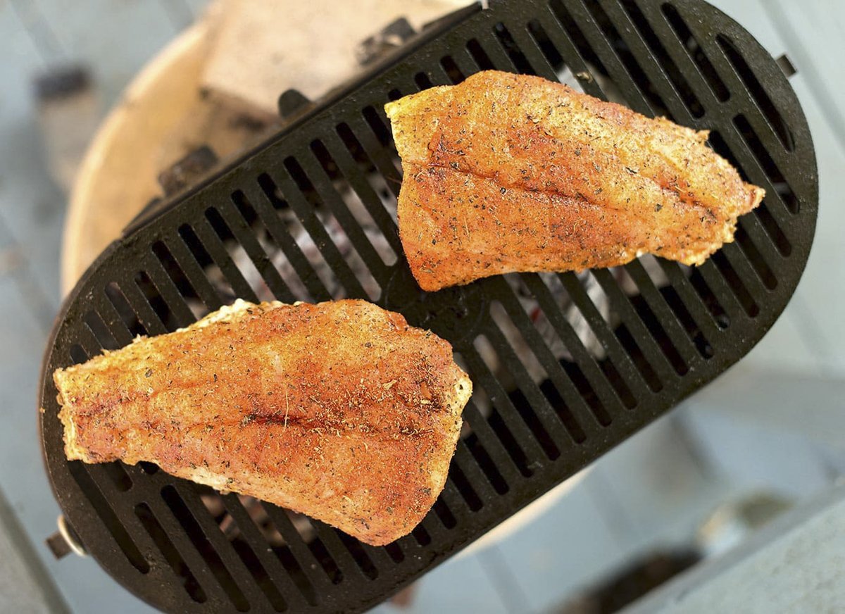 Red fish cooking on a grill.