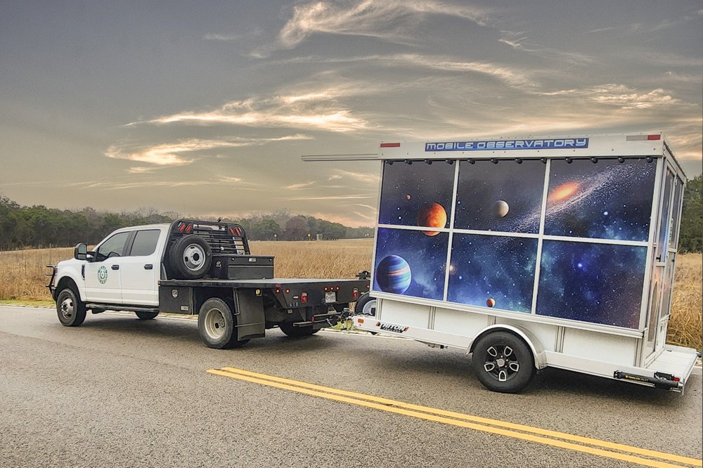 A mobile observatory being pulled by a truck.
