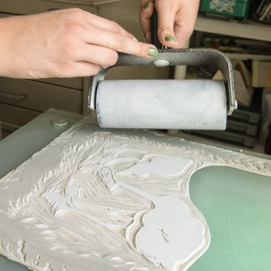An artist rolling ink onto blocks for printing.