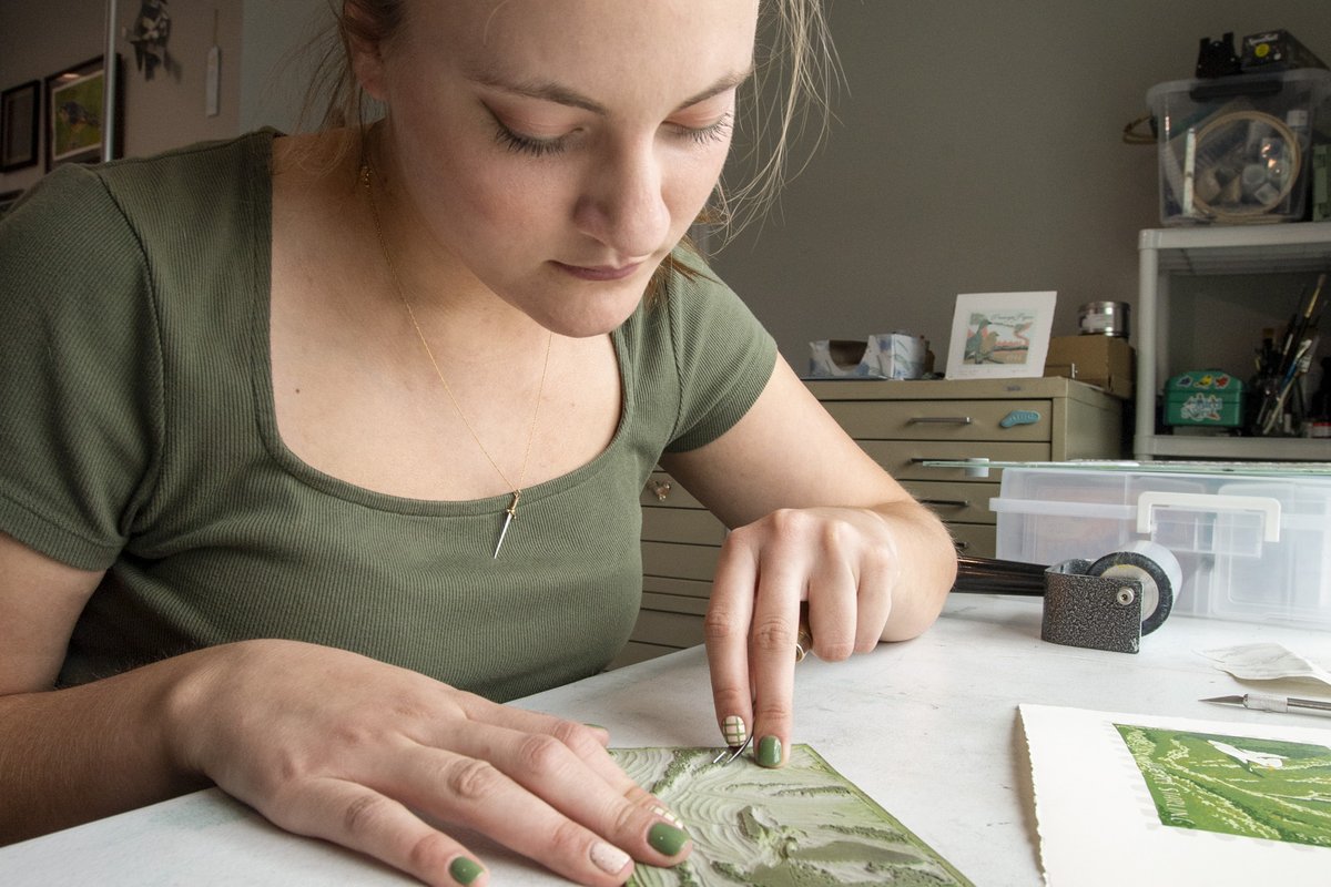 Artist Raylee Schobel pressing inked printing blocks to paper.