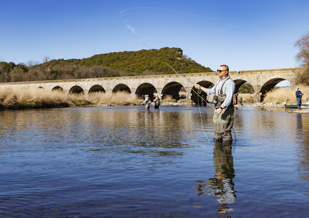 A person fishing under the dam at Mineral Wells.