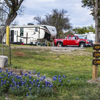 Inks Lake State Park campsite with bluebonnets in foreground and a truck with trailer camper in background