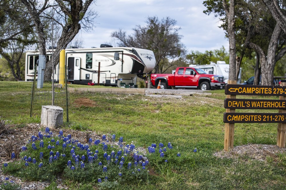Inks Lake State Park campsite with bluebonnets in foreground and a truck with trailer camper in background