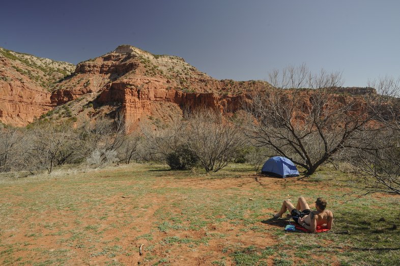 Man lays down besides tent under Caprock Canyons