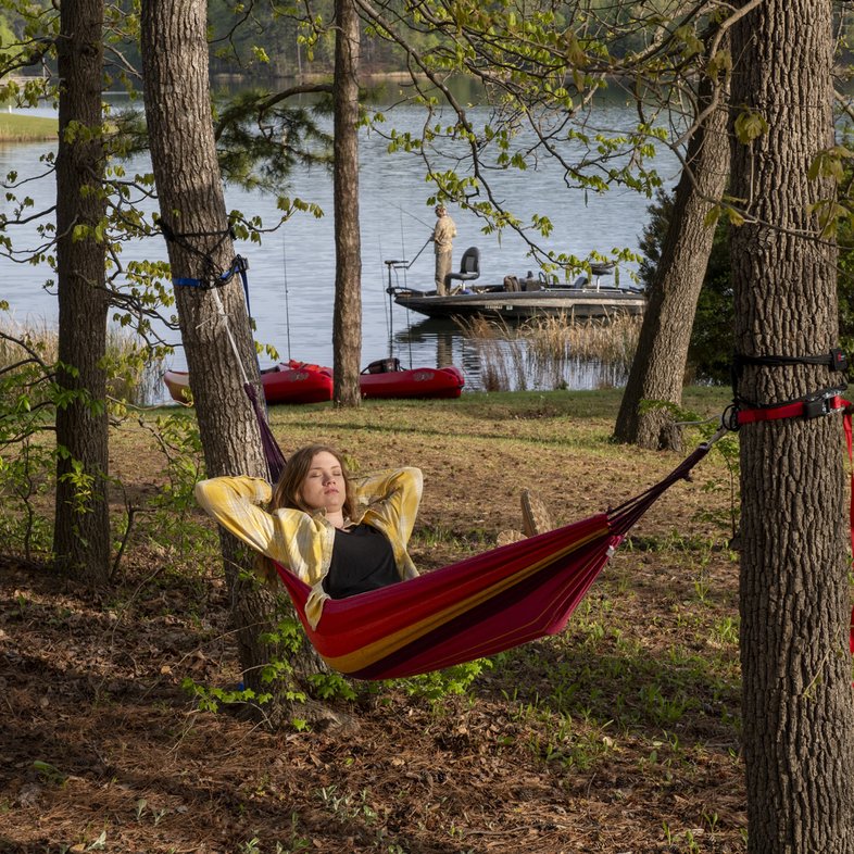 A woman lays in a hammock near lake at Tyler State Park