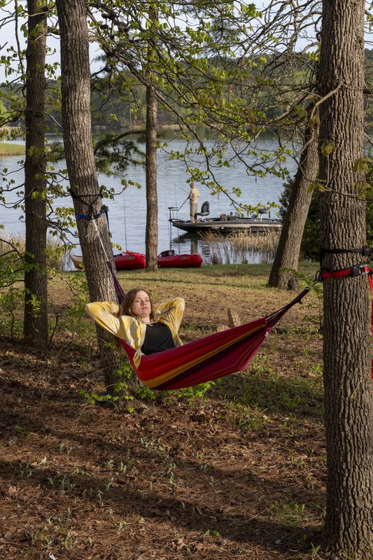 A woman lays in a hammock near lake at Tyler State Park