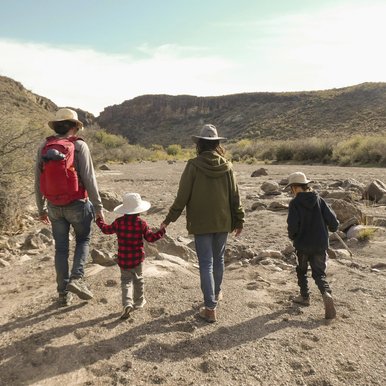 Two adults and two children walk in a dry stream bed at Big Bend Ranch State Park.