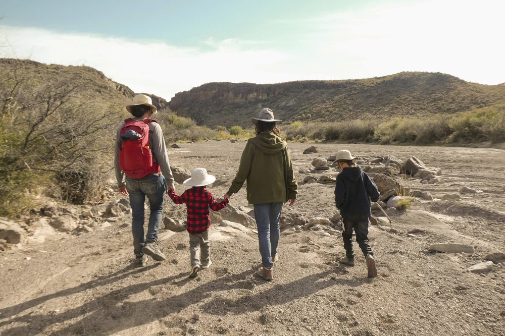 Two adults and two children walk in a dry stream bed at Big Bend Ranch State Park.