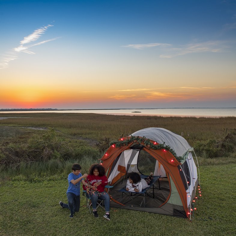 Three people near a tent in Galveston Island State Park