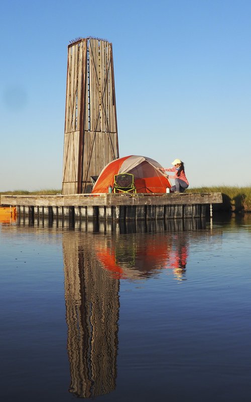 Woman sets up tent on a dock