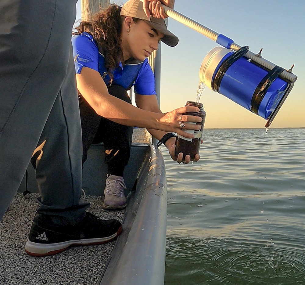 A woman collects ocean water from a boat