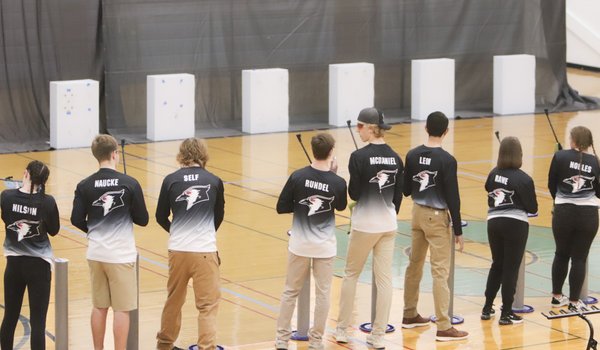 A group of students take aim at targets with air rifles