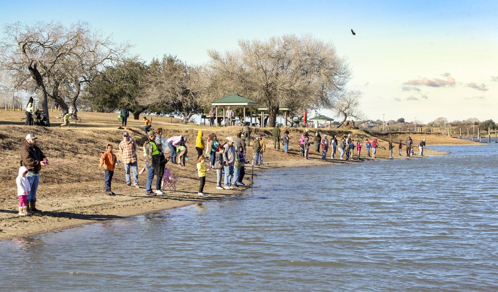 A large group of anglers on the shore of a lake