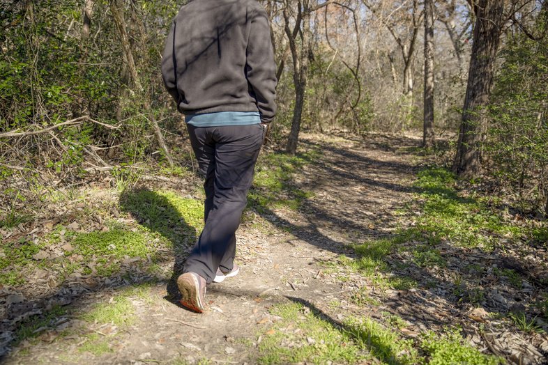 A man walks down a dirt trail