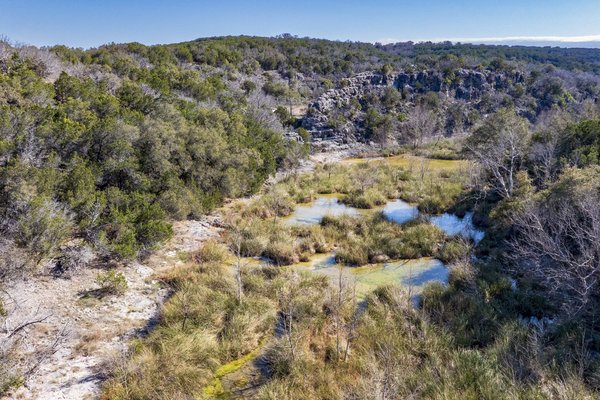 An aerial image of a wooded river bed