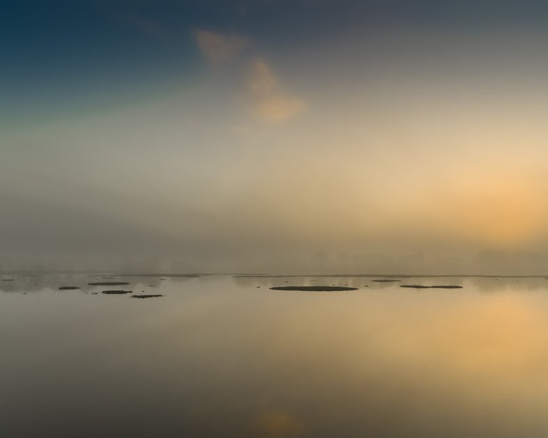 A misty lake with items floating in the water.