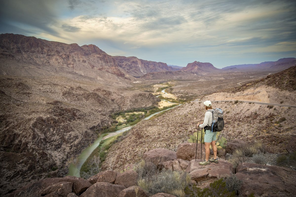Man standing on a hill looking down at a river.